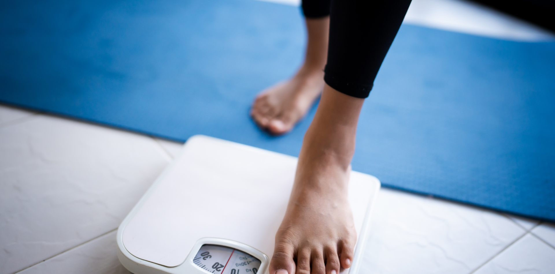 A woman using weighing machine as feature image for weight loss research blog